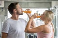 couple young fitness people drinking orange juice bottles in gym. sports man and woman exercises Royalty Free Stock Photo