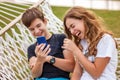 Couple of young happy teenagers. A girl and a guy laugh and watch a video together on a smartphone Royalty Free Stock Photo