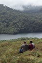 Couple of young hikers contemplating the lagoon of volcanic origin with a view of the green hills full of vegetation of the dry