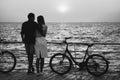 Couple of young hipster lovers hugging at the beach, looking at each other during the sunrise at wooden deck summer time Royalty Free Stock Photo