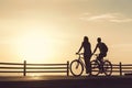 Couple of young hipsters together at the beach at sunrise sky at wooden deck summer time looking at sunset