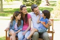 Couple with young kids sitting on park bench Royalty Free Stock Photo