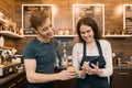 Couple of young male and female coffee shop owners near the counter, talking and smiling, coffee shop business concept Royalty Free Stock Photo
