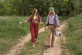 Couple of young people in hippie style on a country road. The girl is dancing, the guy is carrying a retro cassette recorder Royalty Free Stock Photo