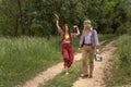 Couple of young people in hippie style on a country road. The girl is dancing, the guy is carrying a retro tape recorder Royalty Free Stock Photo