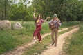 Couple of young people in hippie style. A girl is dancing, a guy is playing a guitar on a country road Royalty Free Stock Photo