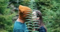 Couple of young people in love kissing behind fern leaf in forest. Unrecognizable happy man hipster in hat and young