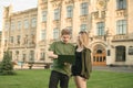 Couple of young people using laptop while standing on campus at university on lawn, background of main entrance building. Smart Royalty Free Stock Photo