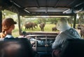 Couple young people watch wild elephants on safari tour in national park in Africa.