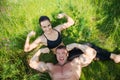 Couple of young sportsmen lie on green grass after workout outdoors Royalty Free Stock Photo