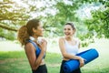 Couple of young sporty woman holding yoga mats and talking together at public park in the morning,Happy and smiling,Relaxing time