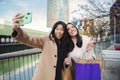 A couple of young women having fun and posing doing a selfie portrait with a cellphone, two girls taking a photo with a Royalty Free Stock Photo