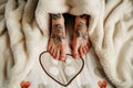 couples feet with matching tattoos under a heartprint blanket