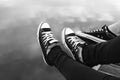 Couples feet in sneakers relaxing by the water.