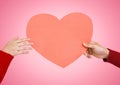 Couples hands holding heart against pink background Royalty Free Stock Photo