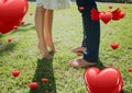 Couples legs in garden with digitally generated red valentines hearts