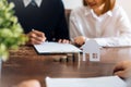 Couples signed a contract to buy a house from the broker. Coin to stack money and model houses placed on the table.