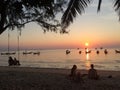 Couples swing watching the sunset,Some people sit on the beach listening to music.