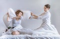 Couples use a pillow to tease each other on the bed