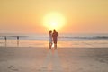 Couples walking on beach at sunset.