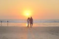 Couples walking on beach at sunset.