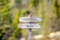 courage fear text carved on wooden signpost outdoors in nature.