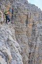 Courageous female climber looking down from high up on via ferrata Cesare Piazzetta, Dolomites mountains, Italy. Summer adventure Royalty Free Stock Photo