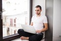 The courageous, handsome, a student working on a windowsill with a laptop. worker communicating on the Internet. Royalty Free Stock Photo