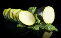 Courgettes cut into slices and leaves on black Royalty Free Stock Photo