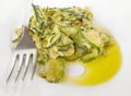 Courgettes with fork on white dish.