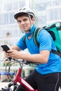 Courier On Bicycle Delivering Food In City Using Mobile Phone