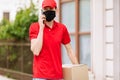 Courier with a cardboard box in a protective medical mask, talking on a mobile phone. Home delivery, quarantine, coronavirus