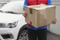 Courier with damaged cardboard box outdoors. Poor quality delivery service Royalty Free Stock Photo