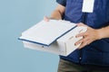 Courier delivering box, offering to sign a paper form, that lies on top of box. Royalty Free Stock Photo