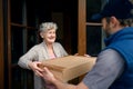 Courier delivering parcel to senior woman, corona virus and quarantine concept. Royalty Free Stock Photo