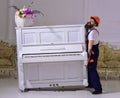 Courier delivers furniture, move out, relocation. Heavy loads concept. Loader moves piano instrument. Man with beard Royalty Free Stock Photo