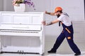 Courier delivers furniture, move out, relocation. Heavy loads concept. Loader moves piano instrument. Man with beard Royalty Free Stock Photo
