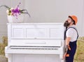 Courier delivers furniture, move out, relocation. Man with beard worker in helmet and overalls lifts up, efforts to move Royalty Free Stock Photo