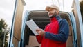 Courier with digital tablet delivering package. Mailman in front the van Royalty Free Stock Photo