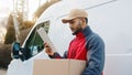Courier with digital tablet delivering package. Mailman in front the van Royalty Free Stock Photo
