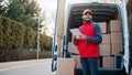 Courier with digital tablet delivering package. Mailman in front the van Royalty Free Stock Photo