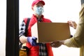 Courier giving cardboard box to woman. Delivery service during coronavirus quarantine Royalty Free Stock Photo