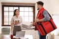 Courier giving order to young woman in office. Food delivery