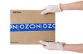 Courier hands in medical gloves holding Ozon online retailer parcel