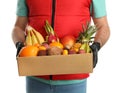 Courier holding box with assortment of exotic fruits on white background, closeup Royalty Free Stock Photo