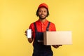 Courier holding cardboard box and smart phone with empty display for delivery service adverisement. Royalty Free Stock Photo