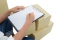 Courier making notes in delivery receipt among parcels on boxes Royalty Free Stock Photo