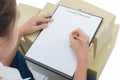 Courier making notes in delivery receipt among parcels on boxes Royalty Free Stock Photo