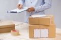 Courier making notes in delivery receipt among parcels at table Royalty Free Stock Photo