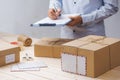 Courier making notes in delivery receipt among parcels at table